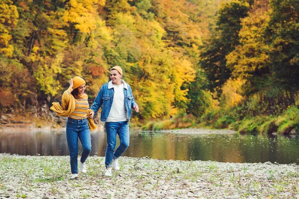 Loving couple running in autumn nature. Autumn mood. Happy man and woman having fun together. Love. Fashionable couple outdoors. Fashion, people and lifestyle. Stylish couple in autumn outfit.