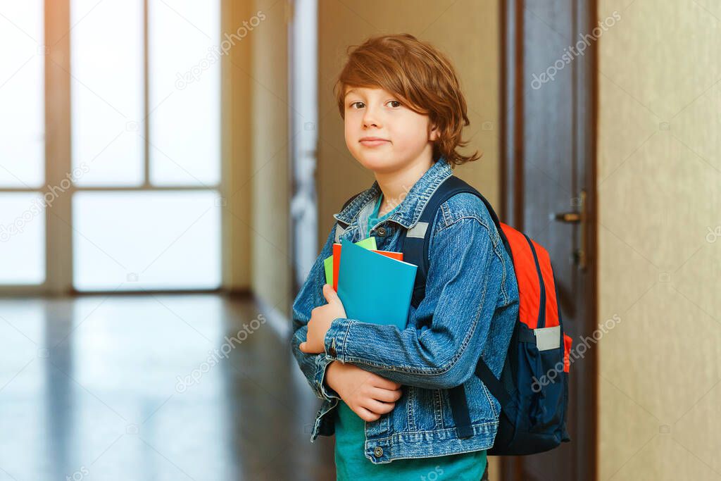 Schoolboy with schoolbag and books in the school. Education concept. Back to school. Schoolkid going to class. Stylish boy with backpack. Boy ready to study.