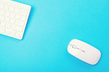 Boş zamanlarınız ve evinizde çalışmanız için modern cihazlar. Evden çalışıyorum. Uzayı kopyala Uzaktan eğitim ve çalışma. Mavi arkaplanda beyaz klavye ve fare, üst görünüm.