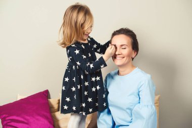 Anne ve kızı makyaj yapıyor. Sevgili anne ve çocuk birlikte eğleniyorlar. Anneler Günün kutlu olsun. Sağlıklı çocuk kozmetik ürünleri. Mutlu sevgi dolu aile.