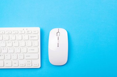 Boş zamanlarınız ve evinizde çalışmanız için modern cihazlar. Evden çalışıyorum. Uzayı kopyala Uzaktan eğitim ve çalışma. Mavi arkaplanda beyaz klavye ve fare, üst görünüm.