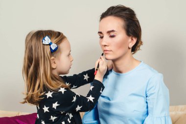 Anne ve kızı makyaj yapıyor. Sevgili anne ve çocuk birlikte eğleniyorlar. Anneler Günün kutlu olsun. Sağlıklı çocuk kozmetik ürünleri. Mutlu sevgi dolu aile.