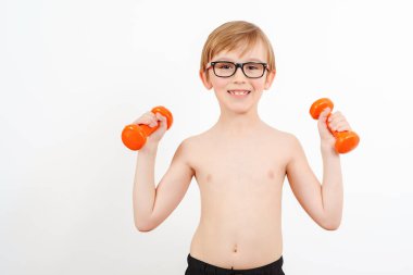 Dambıl kaldıran inek çocuk. Dambılı şirin çocuk eğitimi, beyaz tenli. Çocuk fitness. Vücudumuzu formda tutuyoruz. Çocuk dambıllarla egzersiz yapıyor. Sağlıklı çocukluk, yaşam tarzı.