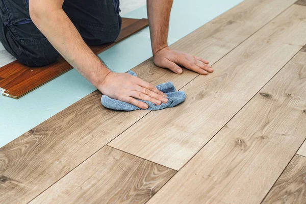 Worker hands installing timber laminate floor. Easy and quick installation of the flooring - connecting laminate locks - DIY floating floor. Man laying laminate flooring - closeup on male hands.