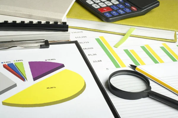 Grafieken, boekhouding, rekenmachine en vergrootglas op houten bureau tafel. Financiële en budgettaire concept. — Stockfoto