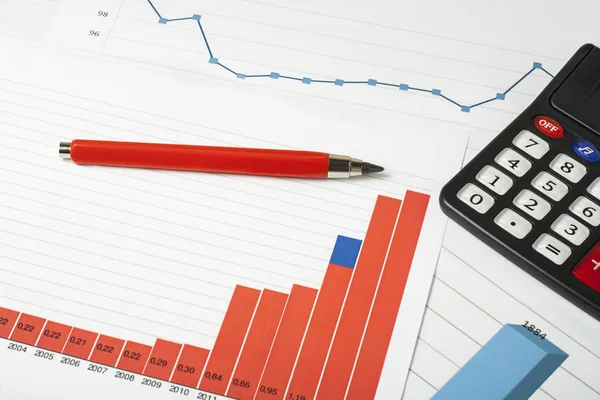 Gráficos, calculadora y pluma en la mesa de oficina para el concepto financiero y empresarial . —  Fotos de Stock