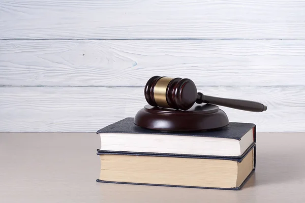 Hukuk kavramı. Bir mahkeme veya icra dairesinde masada hukuk kitapları ile ahşap yargıç tokmak.