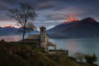 Küçük dağlarda günbatımı ışık arka planda, İtalya ile Lago di Como üzerinde Musso Santa Eufemia Kilisesi 