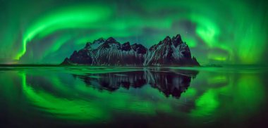 Aurora borealis Stokksnes üzerinde Vestrahorn dağlarda yansımaları beach, İzlanda siyah 