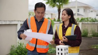 İnşaat mühendisi, müteahhit ve mimar inşaat alanında konuşuyor. Asyalı ustabaşı, inşaat sahasında planları tutuyor. Konut geliştirme projesi.