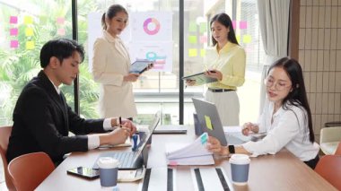 Bir grup mutlu Asyalı genç iş adamı yeni fikirler üretmek ve başarı için stratejiler planlamak için toplantı yapıyorlar. Yavaş çekim videosu.