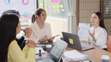 Bir grup mutlu Asyalı genç iş adamı yeni fikirler üretmek ve başarı için stratejiler planlamak için toplantı yapıyorlar. Yavaş çekim videosu.