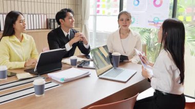 Bir grup mutlu Asyalı genç iş adamı yeni fikirler üretmek ve başarı için stratejiler planlamak için toplantı yapıyorlar. Yavaş çekim videosu.