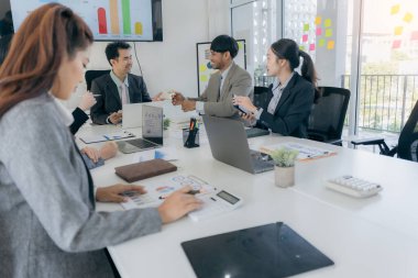 Bir grup iş adamı başarılı takım çalışması gösteren grafikleri tartışıyor. Asyalı iş adamları ofiste beyin fırtınası yapıyor..