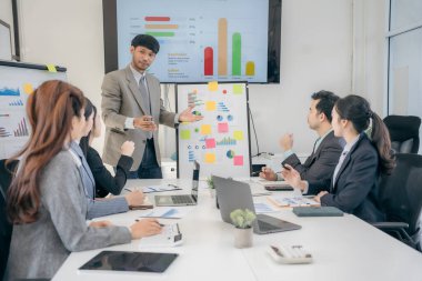 Bir grup iş adamı başarılı takım çalışması gösteren grafikleri tartışıyor. Asyalı iş adamları ofiste beyin fırtınası yapıyor..