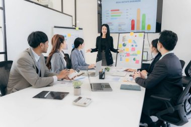 Bir grup iş adamı başarılı takım çalışması gösteren grafikleri tartışıyor. Asyalı iş adamları ofiste beyin fırtınası yapıyor..