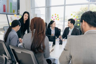 Bir grup iş adamı başarılı takım çalışması gösteren grafikleri tartışıyor. Asyalı iş adamları ofiste beyin fırtınası yapıyor..
