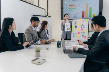 Bir grup iş adamı başarılı takım çalışması gösteren grafikleri tartışıyor. Asyalı iş adamları ofiste beyin fırtınası yapıyor..