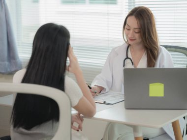 Asian doctor and patient discussing various topics while sitting at table. Concept of medicine and healthcare. Doctor and patient.