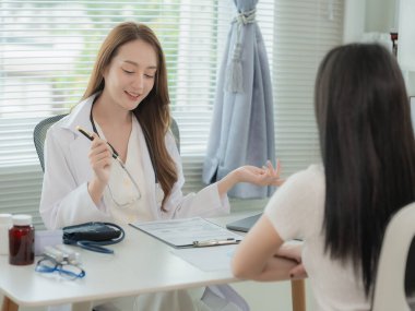 Asian doctor and patient discussing various topics while sitting at table. Concept of medicine and healthcare. Doctor and patient.