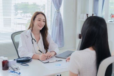 Asian doctor and patient discussing various topics while sitting at table. Concept of medicine and healthcare. Doctor and patient.
