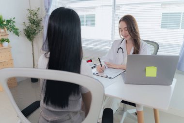 Asian doctor and patient discussing various topics while sitting at table. Concept of medicine and healthcare. Doctor and patient.