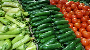 Taze ve doğal kırmızı domates ve salatalık bir meyve pazarında yığılmış