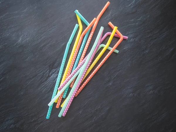 Drinking paper colorful straws for summer cocktails on dark background with copy space. Top view. group of objects