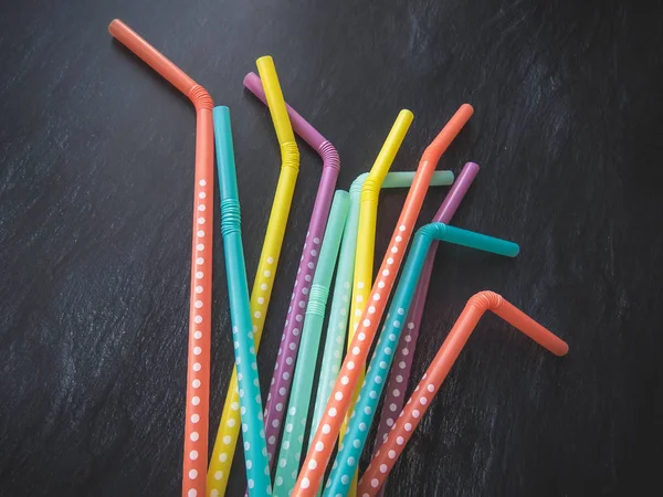 Drinking paper colorful straws for summer cocktails on dark background with copy space. Top view. group of objects