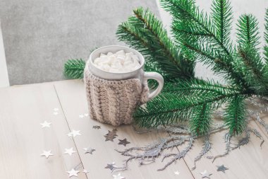 Bir Noel ağacı ve simli yıldız ışık bir ahşap zemin üzerine sıcak örme ceket marshmallow ile beyaz fincan. metin için yer