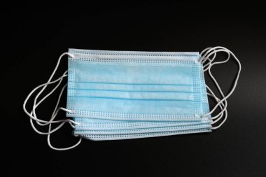 Koronavirüse karşı korunmak için antiviral tıbbi maske. Siyah arka planda cerrahi koruyucu maske. Virüs ve salgın COVID-19 'un yayılmasının önlenmesi.