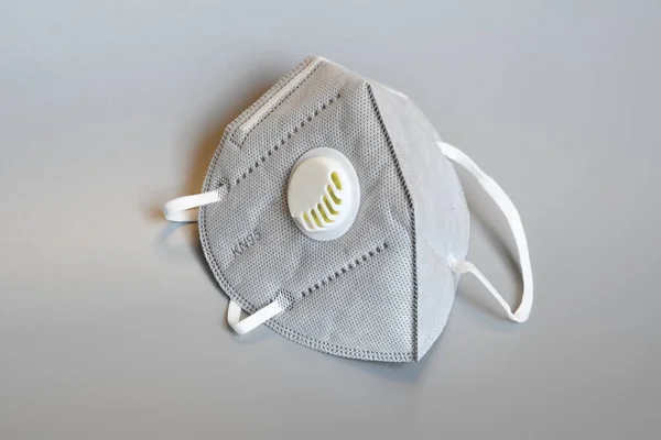 KN95 or N95 mask with valve for protection pm 2.5 and corona virus on grey background. Prevention of the spread of virus and pandemic COVID-19.