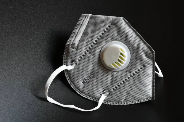 KN95 or N95 mask with valve for protection pm 2.5 and corona virus on black background. Prevention of the spread of virus and pandemic COVID-19.