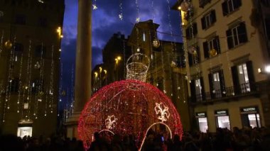 Floransa, Aralık 2019: Noel zamanı Floransa 'nın merkezi. Santa Trinita Meydanı 'nda turistlerle Noel ışıkları süslemeleri. 4K UHD Video. Kamera hareketini yakınlaştır.