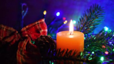 Yeşil köknar ve parlak ışıklarla yanan mum. Noel atmosferi. Odaklan. 4K UHD Video.