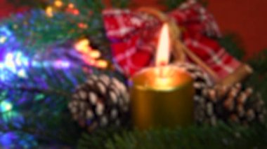 Çam kozalaklı yeşil köknar ağacına altın mum. Arka planda parlak ışıklar ve dekor var. Noel tatili atmosferi. 4K UHD Video.
