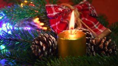 Çam kozalaklı yeşil köknar ağacına altın mum. Arka planda parlak ışıklar ve dekor var. Noel tatili atmosferi. zoom kamera hareketi. 4K UHD Video.
