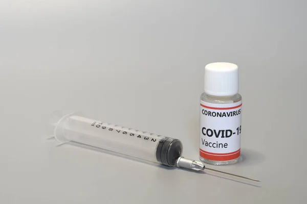 Detail of a syringe with vial containing Covid-19 virus vaccine isolated on gray background. Pharmaceutical research against Coronavirus, concept.