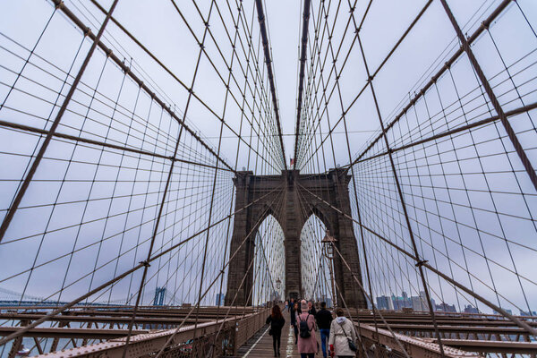 New York, US - March 29, 2018: People crossing the Brooklyn bridge on a foggy day in New York