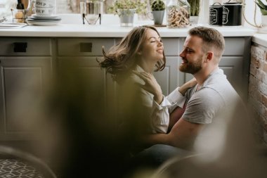 Romantik genç çift mutfakta birlikte yemek yapıyor. Beyaz gömlekli kız. Birlikte kahvaltı.