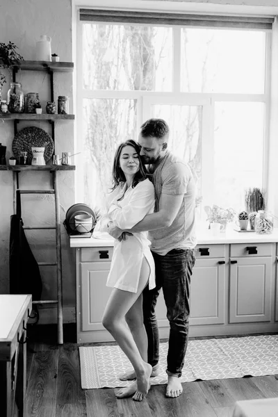 Romantica giovane coppia che cucina insieme in cucina. La ragazza con la camicia bianca. Colazione insieme . — Foto Stock