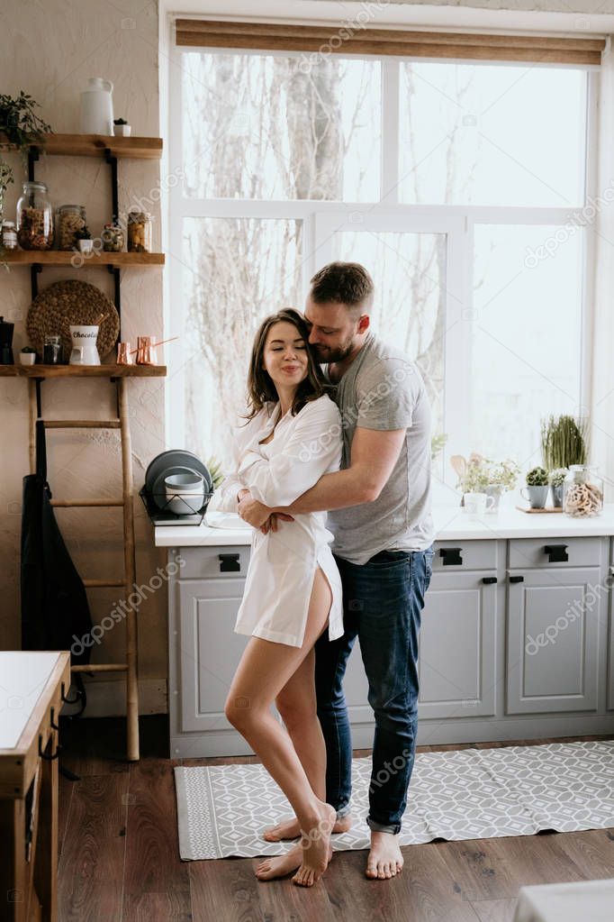 Romantic young couple cooking together in the kitchen. The girl in the white shirt. Breakfast together.