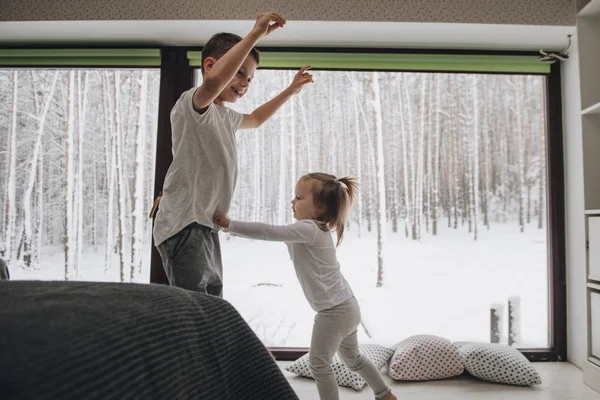 La famille est assise à la fenêtre et regarde la forêt d'hiver. Bon esprit du Nouvel An. Matin en pyjama . — Photo
