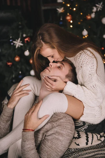 Paar auf dem Bett im Schlafzimmer. Dunkles Interieur. Neujahr und Weihnachten. Umarmungen und Küsse. Liebe. Weißer Pullover und hohe Socken. Romantisches Treffen. Ein Date. — Stockfoto