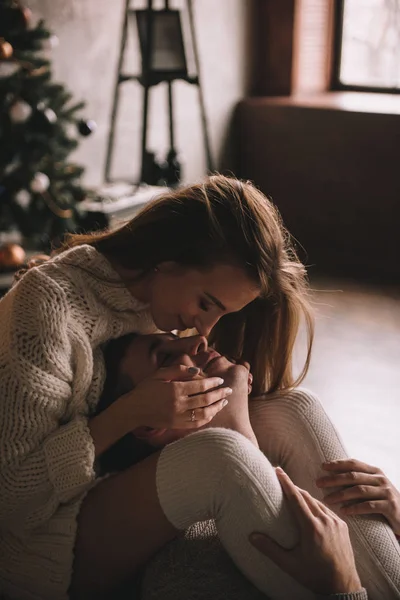 Paar auf dem Bett im Schlafzimmer. Dunkles Interieur. Neujahr und Weihnachten. Umarmungen und Küsse. Liebe. Weißer Pullover und hohe Socken. Romantisches Treffen. Ein Date. — Stockfoto