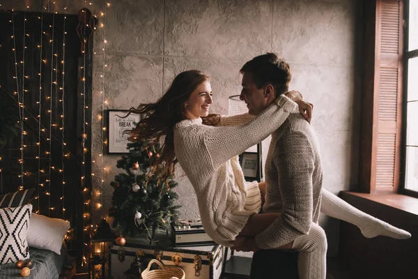 Coppia sul letto in camera da letto. Interno scuro. Capodanno e Natale. Abbracci e baci. Con amore. Maglione bianco e calzini alti. Incontro romantico. Un appuntamento amanti. — Foto Stock