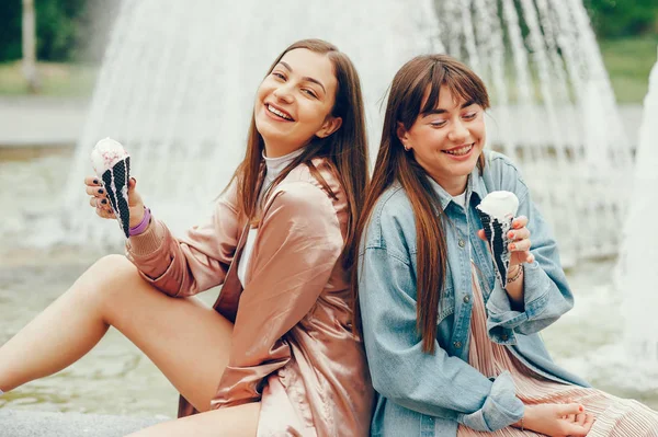 Çeşme ve gidiş dondurma yakın oturan iki kız. — Stok fotoğraf