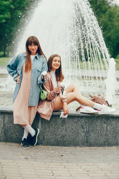 Δύο κορίτσια που κάθονταν κοντά στην κρήνη και πηγαίνοντας με παγωτό. — Φωτογραφία Αρχείου