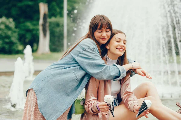 两个女孩坐在喷泉边去吃冰淇淋. — 图库照片