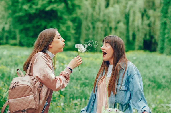 Hermosas ladys descansando en el parque y jugando con diente de león . —  Fotos de Stock